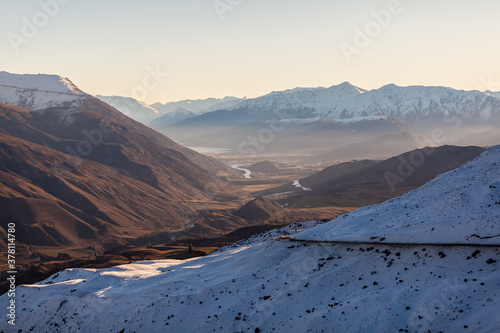 Views of snow covered mountains looking towards Frankton and Queenstown from the Crown Ranges just before dusk during winter. Arrow Junction, New Zealand.