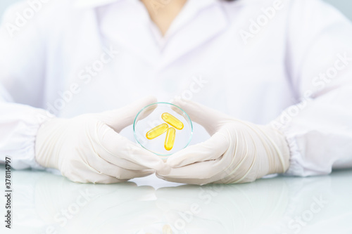Scientist holding Omega 3 capsule in labcoat