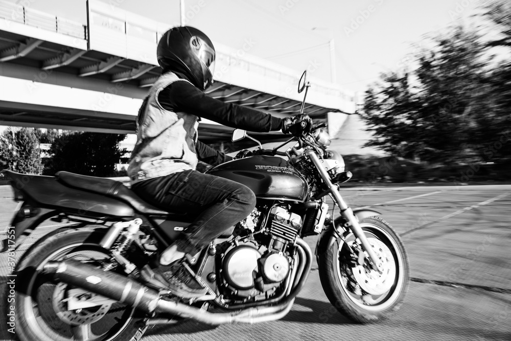 Naklejka premium Man rides a motorcycle in the city.Motorcyclist riding a bike during the day on the road.Black and white photo
