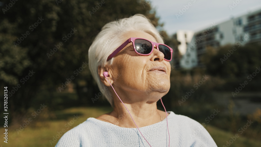 Senior woman with pink sunglasses in the park looking at the distance. High quality photo Senior woman with pink sunglasses in the park looking at the distance. High quality photo