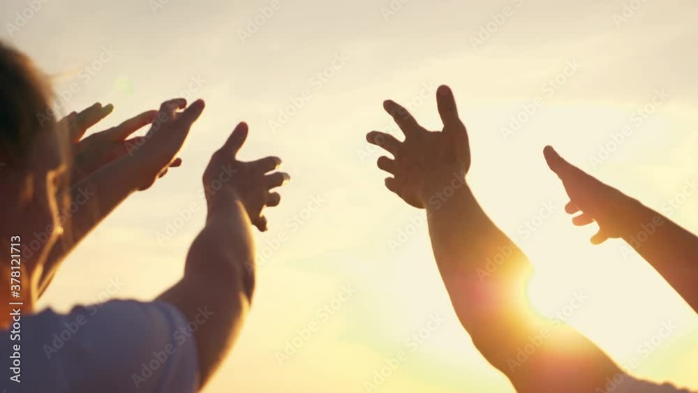 People's hands reach for the sun at sunset. Happy family together. Teamwork. A cry for help, People together in prayer turn to the sun. People's hands reach for the sun at sunset. Happy family together. Teamwork. A cry for help, People together in prayer turn to the sun.