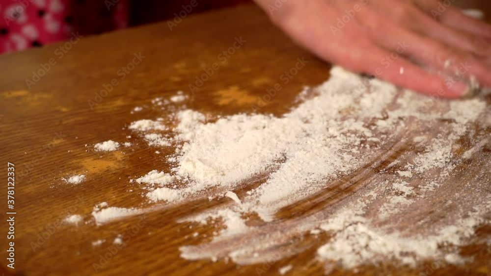 hands roll out a sheet of dough with a rolling pin on a wooden table. hands roll out a sheet of dough with a rolling pin on a wooden table.