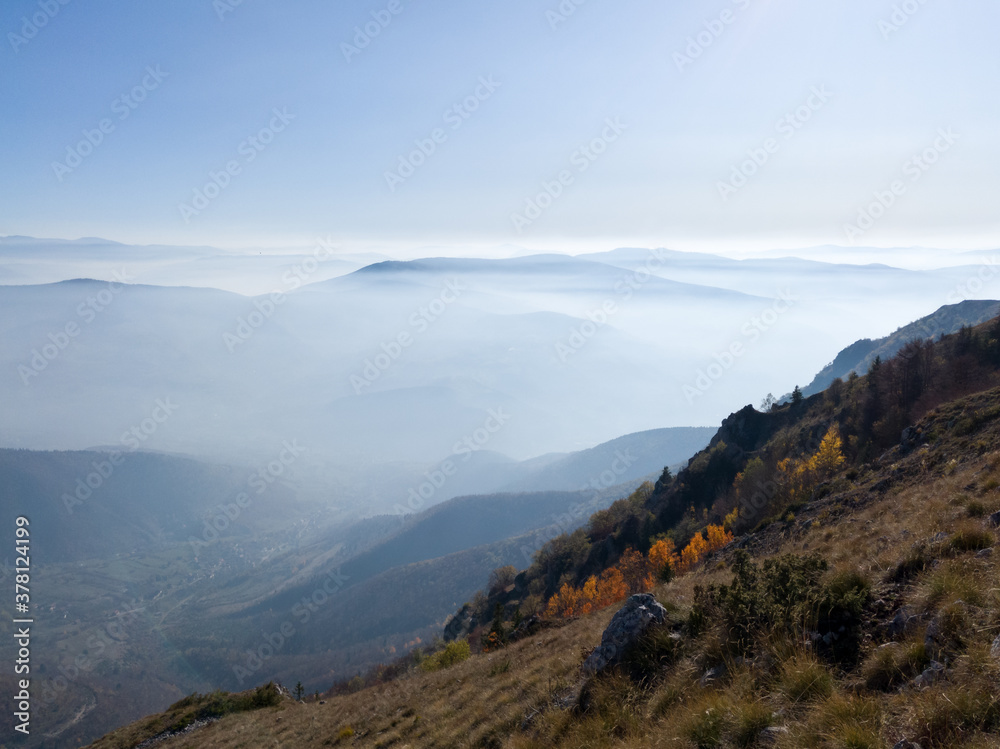 Fototapeta premium Scenic view from Vlašić mountain to the valley filled with fog and mountain peaks above the fog in autumn during a sunny day