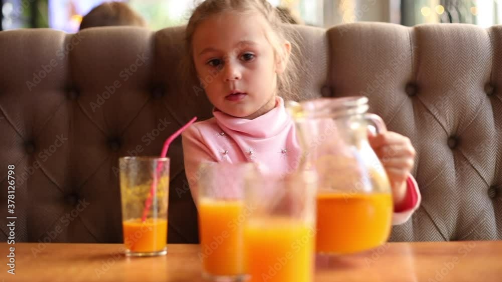 Cute little girl drinking sea buckthorn fruit drink in a cafe
Cute little girl drinking sea buckthorn fruit drink in a cafe