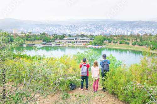 Three young friends standing and looking to panorama of turtle lake and Tbilisi Vake districts buildings in the background. Travel and tourism in Georgia.