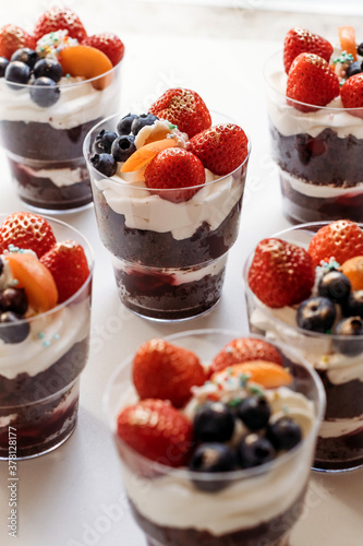 Festive cake for the birthday. Сakes with cream and berries. Desserts for adults and children on table. Festive cupcakes with chocolate and berries. Vertical photo.