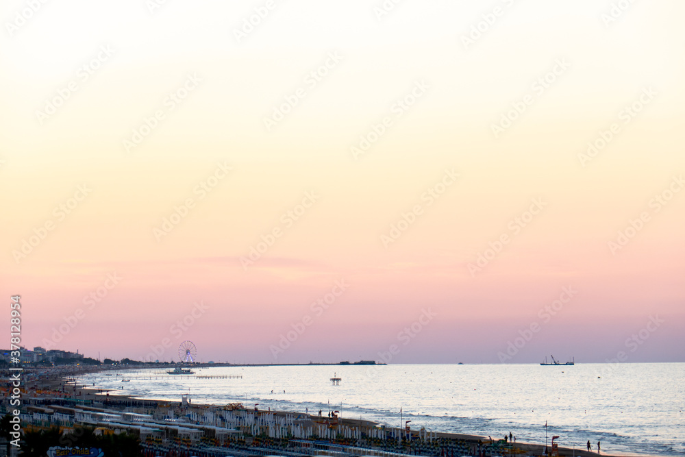 Vista della costa di Riccione con la ruota panoramica di Rimini e il mare Adriatico al tramonto