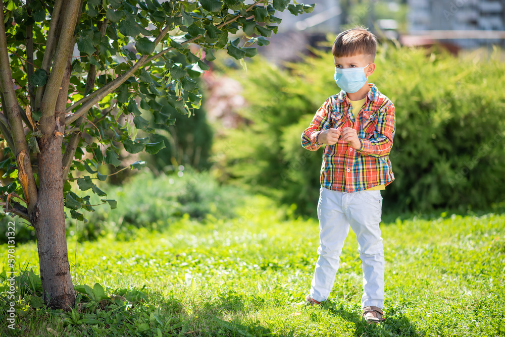 A child wearing a medical mask plays outdoors during the coronavirus and Covid-19 pandemic