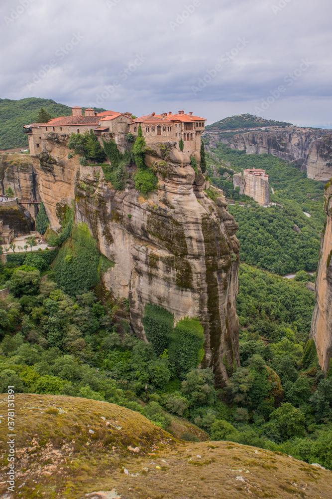 Vertical photo of  Varlaam Monastery. Beautiful scenic panoramic view, ancient traditional greek building on the top of huge stone pillar in Meteora,Thessaly, Greece, Europe on a cloudy day.