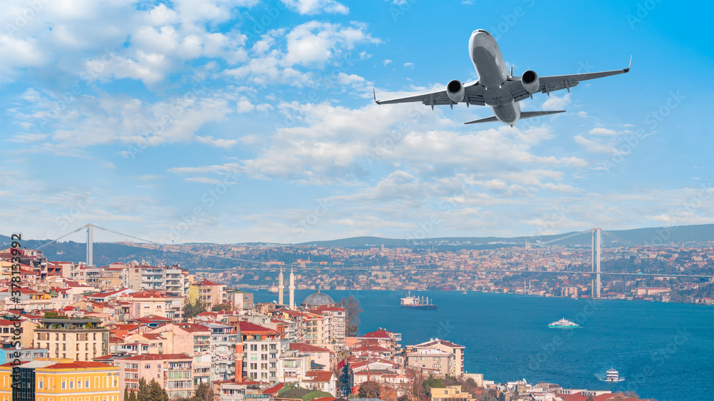 Fototapeta premium A passenger airplane is flying over istanbul city with blue Bosphorus sea and bridge