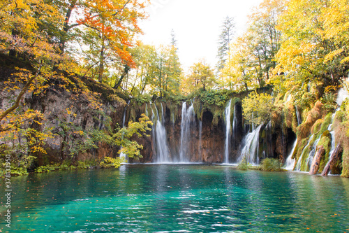 Autumn landscape with waterfalls and amazing lake. Yellow and orange trees near blue water. The Plitvice Lakes National Park in Croatia. © Marina April