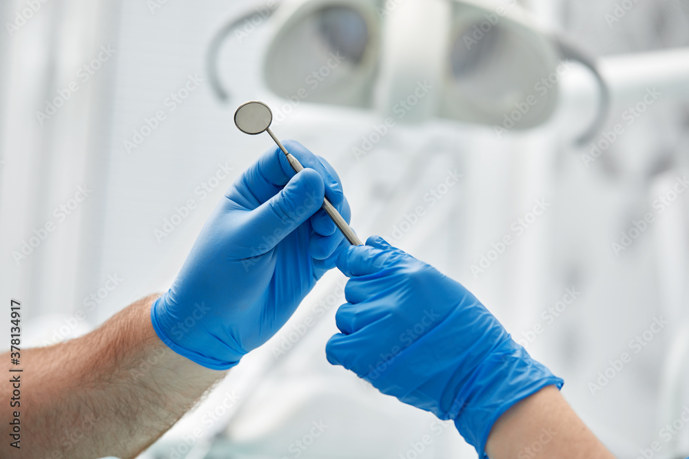 Close-up of the hands of a dentist and nurse surgeon over an operating room during a dental implant operation Close-up of the hands of a dentist and nurse surgeon over an operating room during a dental implant operation