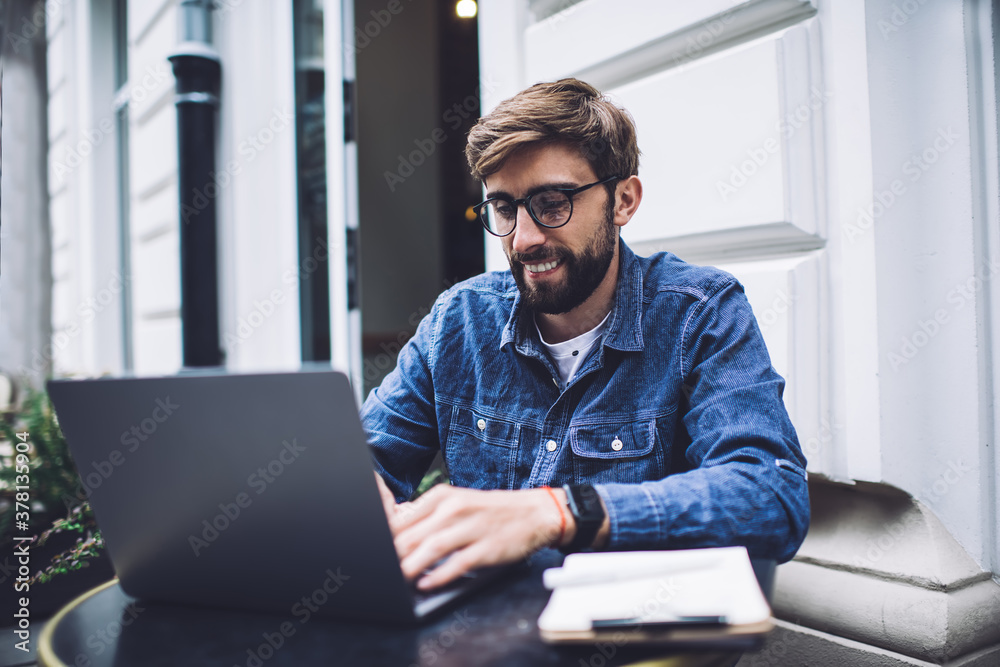 Male blogger typing on laptop on street Male blogger typing on laptop on street