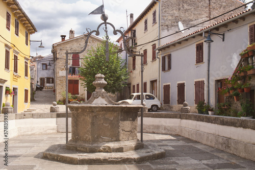 The town center with traditional historic houses, medieval well and retro car in the small Istrian city Buzet, Croatia