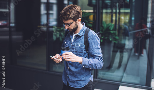 Focused male messaging on smartphone near building