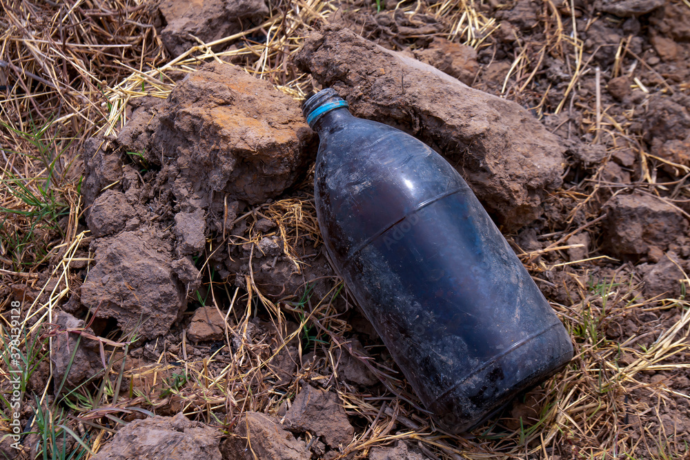 Obraz premium bottle glass insecticide garbage on the farmer ground, polluted waste concept, garbage waste of pesticides bottle on floor, contaminated waste
