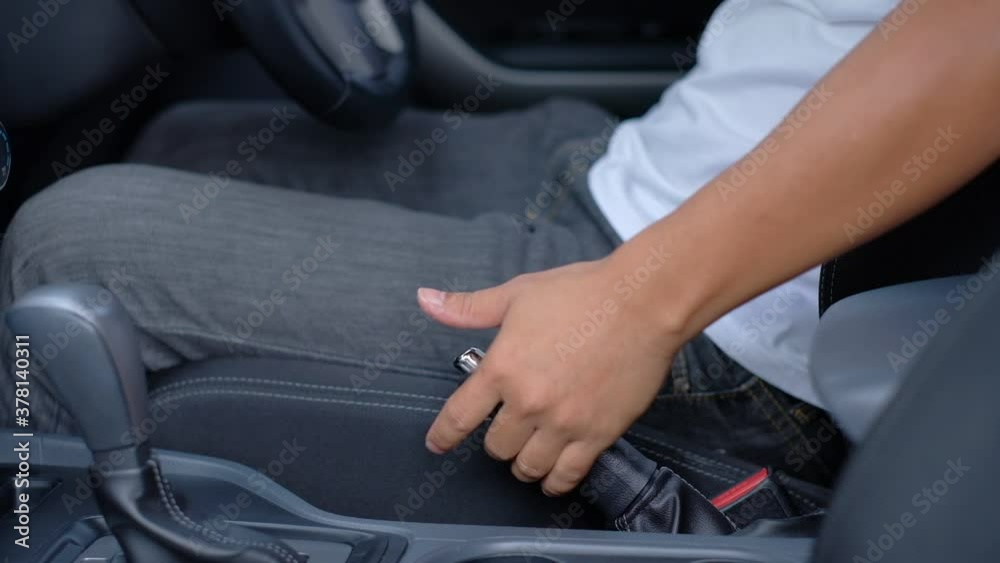 The driver releases the handbrake down to drive the car away.