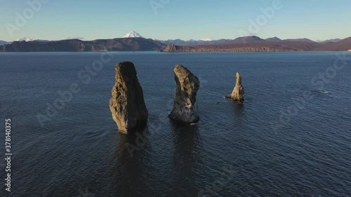 Autumn scenery, beautiful sunrise over Avacha Bay on Russia's Kamchatka Peninsula, and the famous Three Brothers Rock. The waters of the Pacific Ocean. In the background is the Avachinsky volcano.