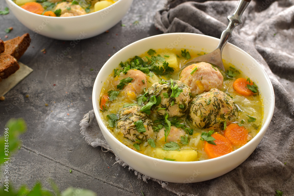 Meatball soup with noodles and carrots. Dark gray background. Gray linen napkin. Close-up. Healthy lunch, soup with herbs and meat. Meatball soup with noodles and carrots. Dark gray background. Gray linen napkin. Close-up. Healthy lunch, soup with herbs and meat.