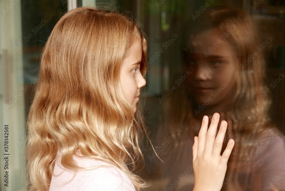 Fototapeta premium Girl smiling as she looks at her reflection in a sliding glass door