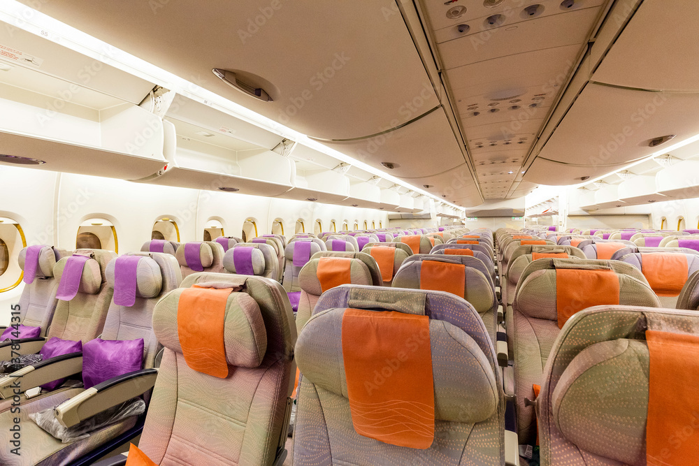 Fototapeta premium Rows of empty seats on a modern wide body jet aircraft, overhead bins open and waiting for luggage when passengers board the economy section of the aircraft.