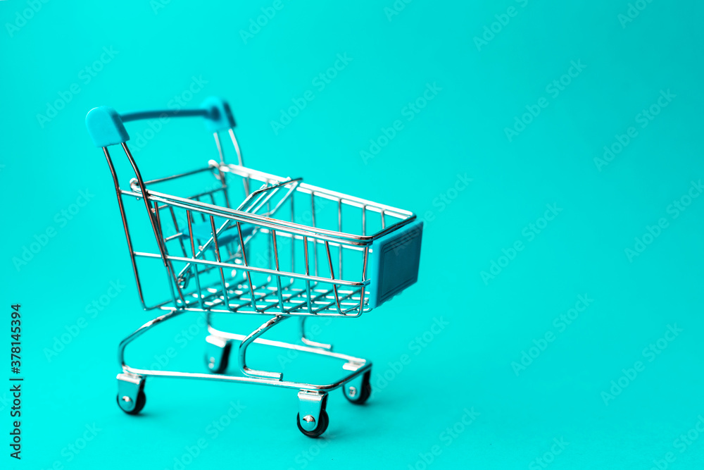 empty metal shopping trolley on green background. Discount and shopping concept