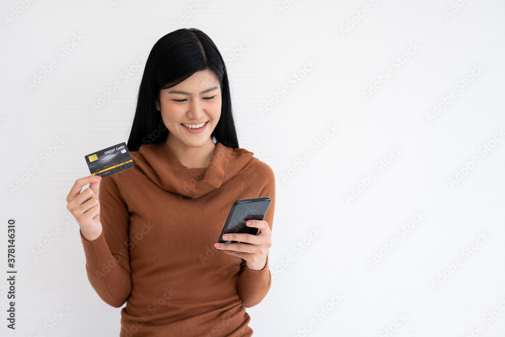Happy Asian woman holding card credit and smartphone for mobile banking on the internet. Concept of new lifestyle and financing technology. Happy Asian woman holding card credit and smartphone for mobile banking on the internet. Concept of new lifestyle and financing technology.