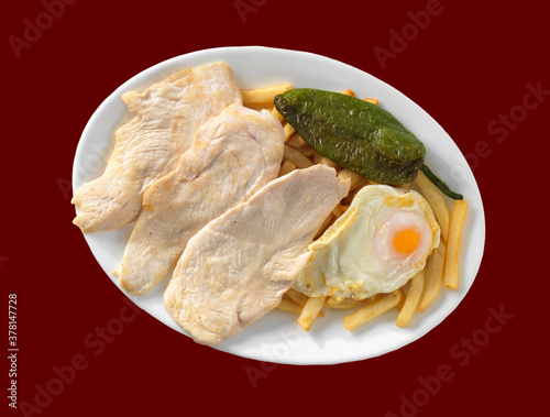 plato combinado filete de lomo huevo frito pimiento patatas, en plato y fondo rojo photo