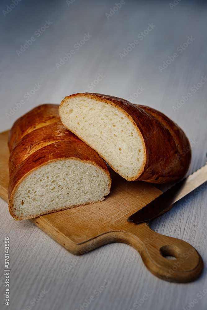 Delicious freshly baked bread and a knife on the kitchen board