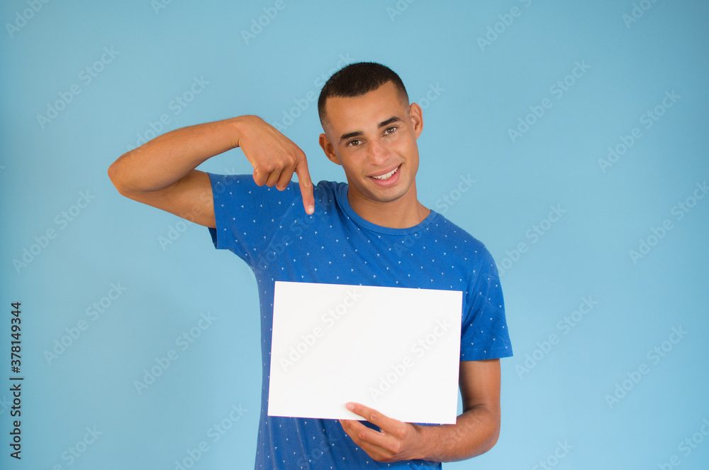 Handsome young man is holding a sheet of paper and pointing on it