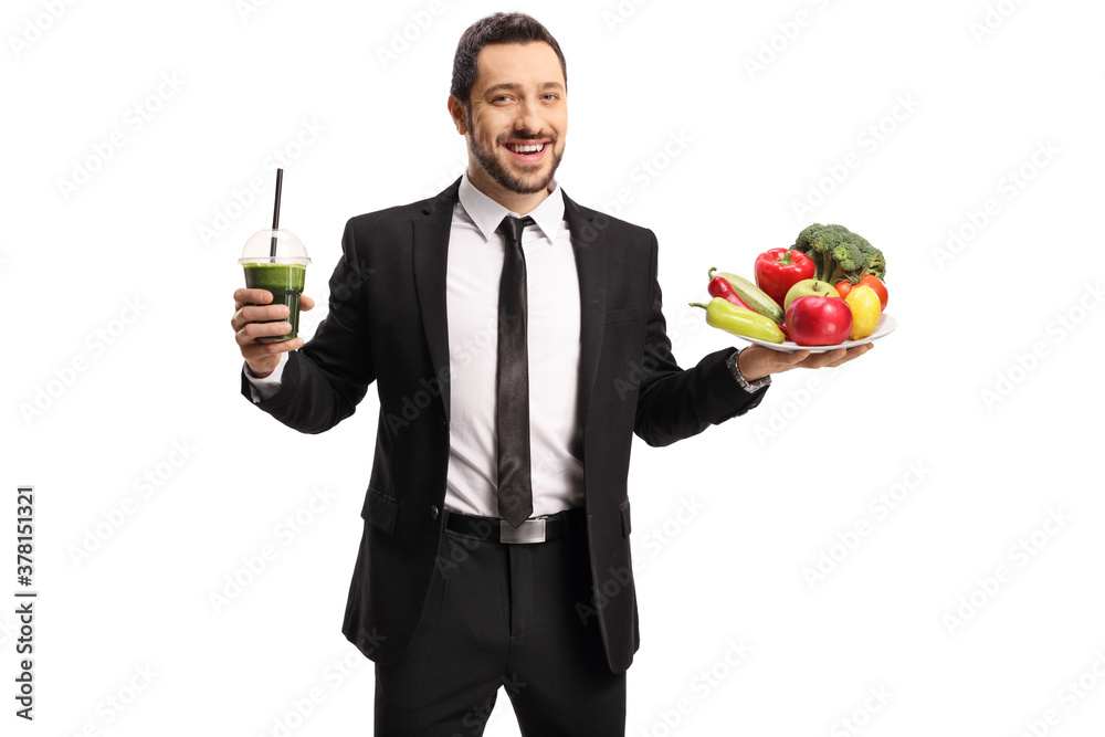 Smiling professional man in a suit holding a healthy green smoothie and a plate of fruits and vegetables Smiling professional man in a suit holding a healthy green smoothie and a plate of fruits and vegetables