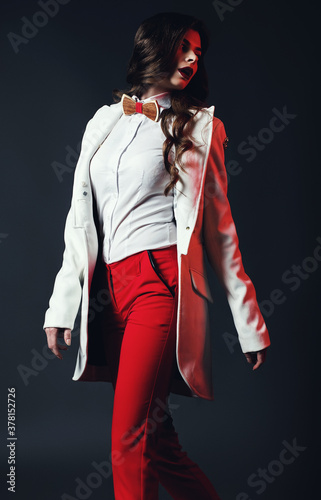Woman in red pants and white coat walking in red light