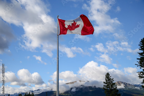 The national flag of Canada against a blue sky in the Canadian Rockies