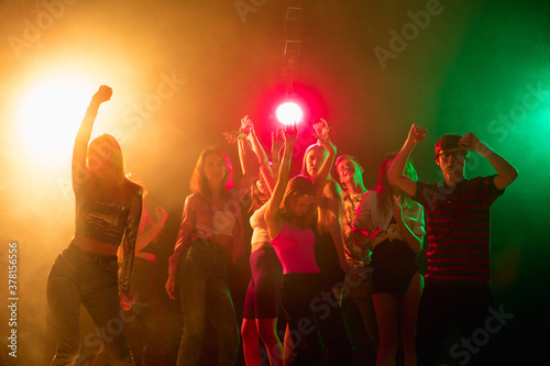 Shadows. A crowd of people in silhouette raises their hands, dancing on dancefloor on neon light background. Night life, club, music, dance, motion, youth. Bright colors and moving girls and boys.