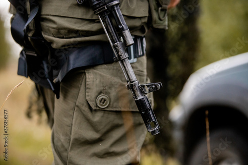 Close-up, Kalashnikov assault rifle, on the chest of a military man. There is a tint. Special forces team. Russian police (Spetsnaz). photo