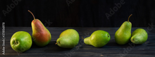 Green ripe pear on black wooden background.