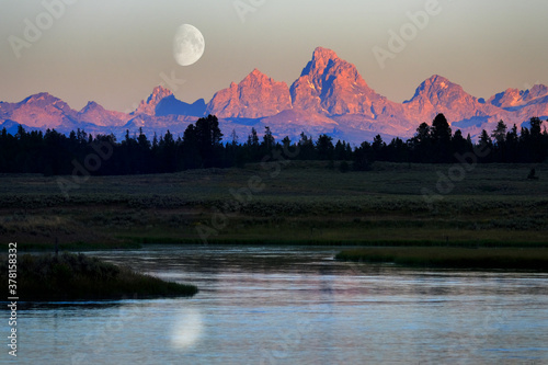 Sun Setting On Teton Mountain Range Tetons with River Flowing and Moon © Lane Erickson