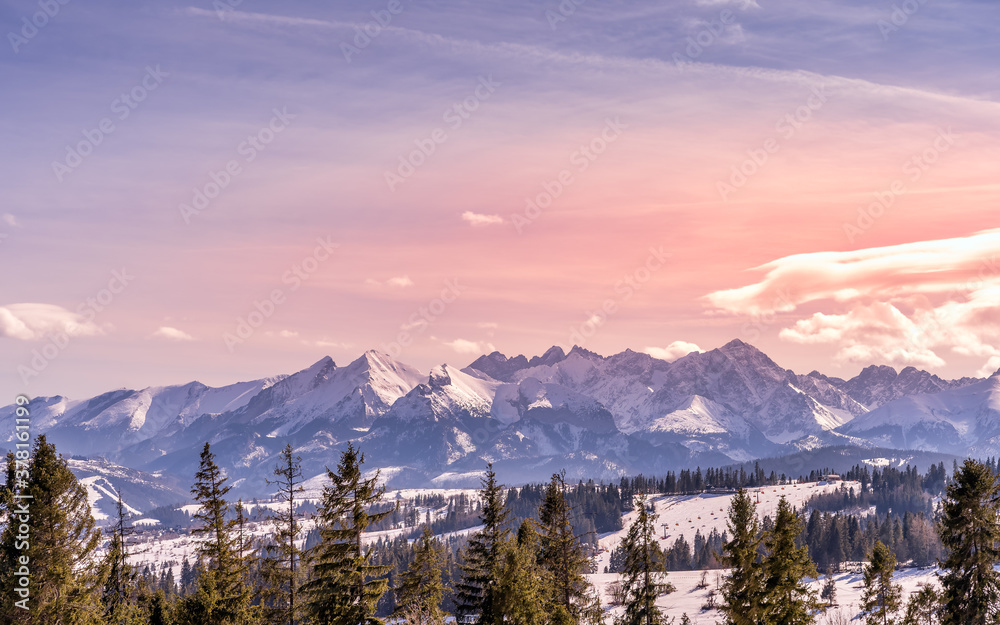 Sunset with dramatic sky and panoramic view on forest and snowy Tatra Mountains in winter time. Ski slopes and ski lifts in Bialka Tatrzanska, Poland