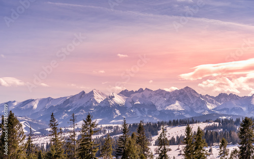 Sunset with dramatic sky and panoramic view on forest and snowy Tatra Mountains in winter time. Ski slopes and ski lifts in Bialka Tatrzanska, Poland