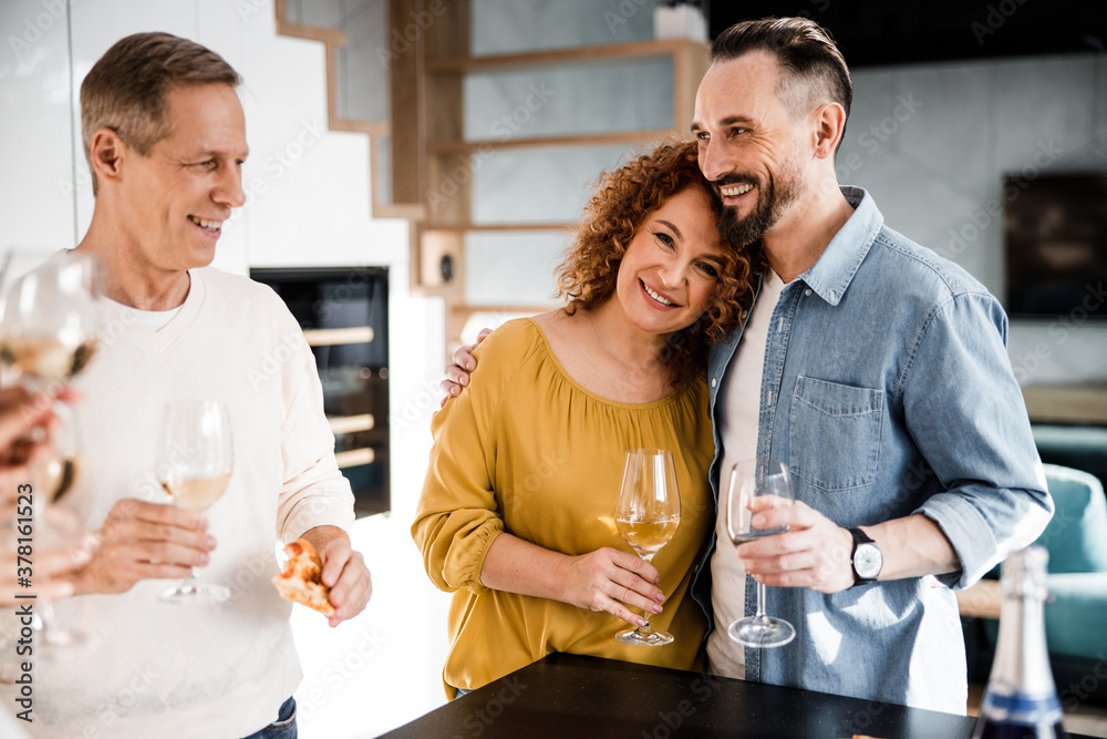Smiling couple is posing at camera and holding wine Smiling couple is posing at camera and holding wine