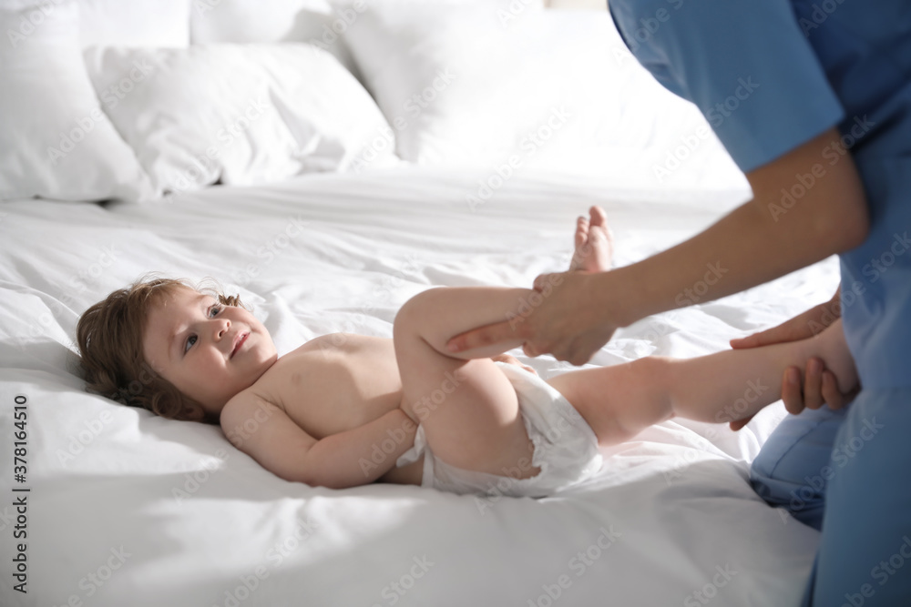 Orthopedist examining cute little baby on bed