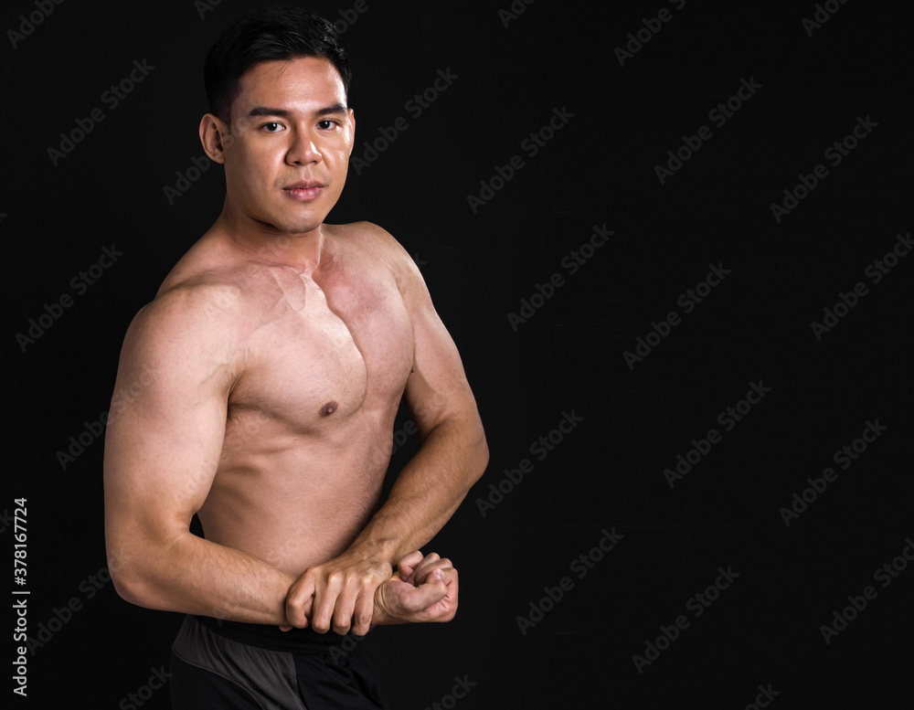 Fototapeta premium Portrait of asian muscular man standing on black background