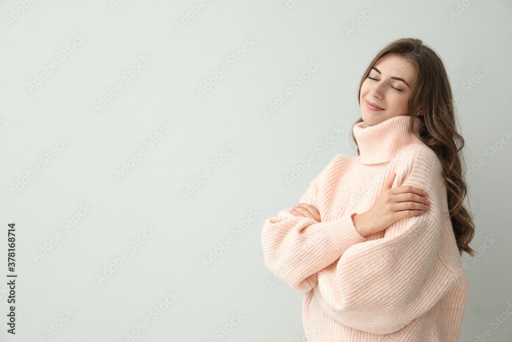 Beautiful young woman wearing warm pink sweater on light background. Space for text