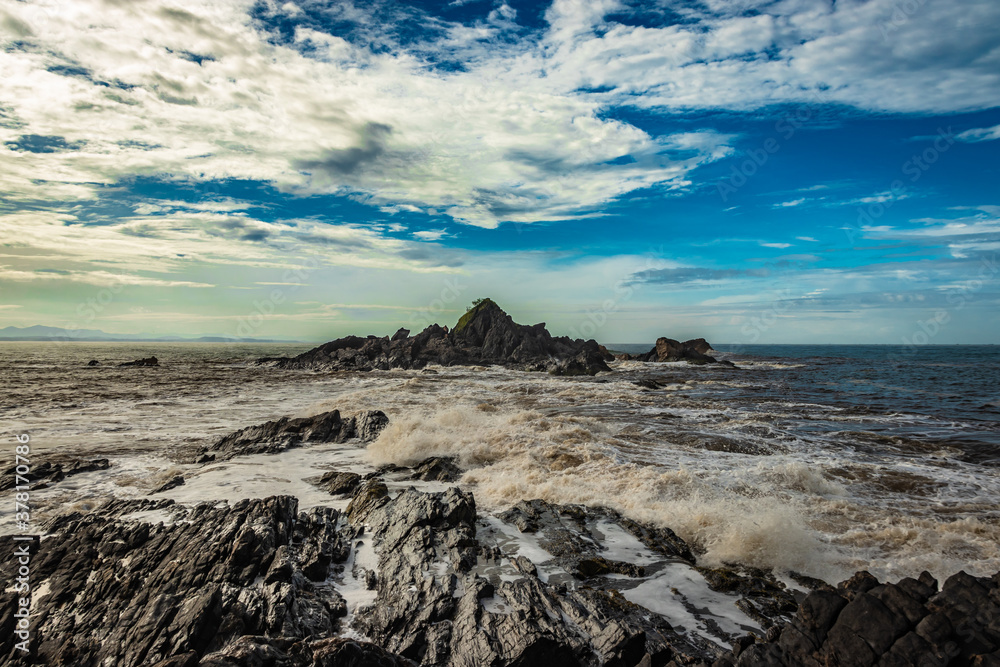 rocky sea beach with crashing waves and amazing sky at morning from flat angle