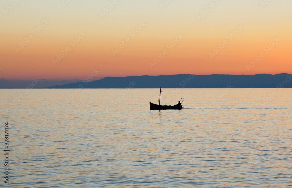 Fishing boat at sunset around the bay of Kardamyli village in Messiniaki Mani region of south Peloponnese in Greece.