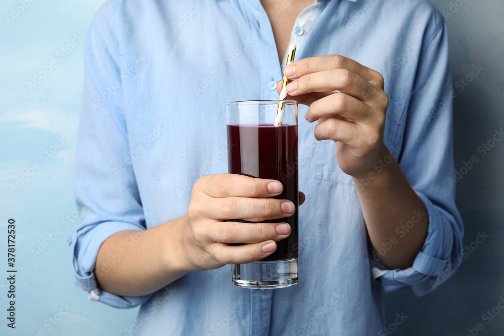 Woman with glass of juice on light blue, closeup Woman with glass of juice on light blue, closeup