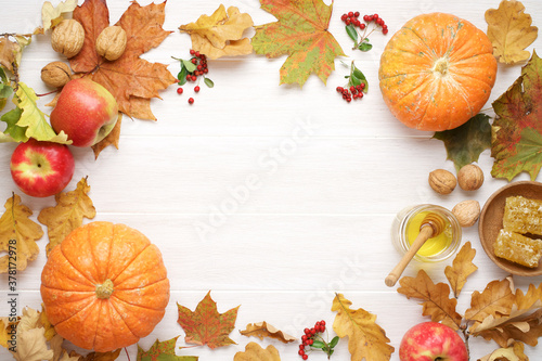 Bright autumn leaves, walnuts, honey, apples, berries on white wooden table. Festive fall seasonal decor for Thanksgiving day or Halloween