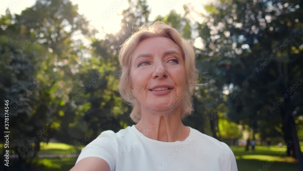 Happy senior woman relaxing in park talking on video call with family Happy senior woman relaxing in park talking on video call with family
