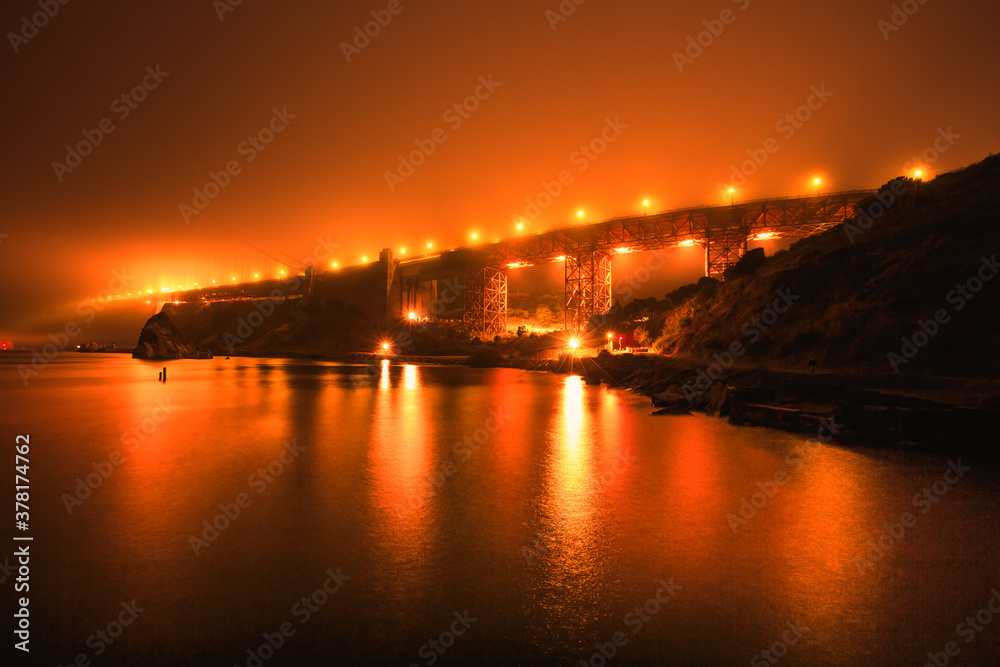 night view of orange sky of San Francisco Golden Gate bridge, from Moore Rd Pier. California fires in September 2020 in United States. Wildfires composition.