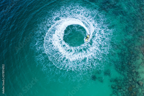 People are playing a jet ski in the sea.Aerial view. Top view.amazing nature background. The color of the water and beautifully bright. © MAGNIFIER